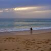 Surfer walking beach at sunset